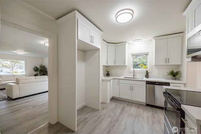 kitchen featuring white cabinets, appliances with stainless steel finishes, light countertops, and a sink