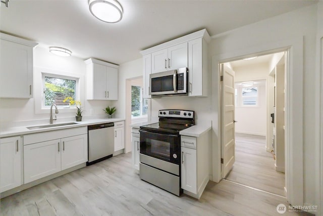 kitchen featuring light countertops, white cabinets, appliances with stainless steel finishes, and a sink