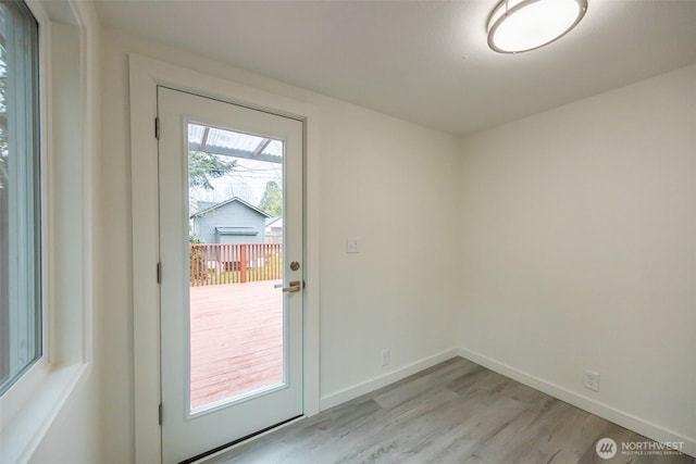 doorway featuring baseboards and light wood-style floors