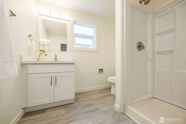 bathroom with vanity, wood finished floors, baseboards, a stall shower, and toilet