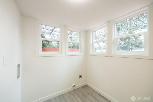 laundry area with electric dryer hookup, light wood-type flooring, baseboards, and laundry area