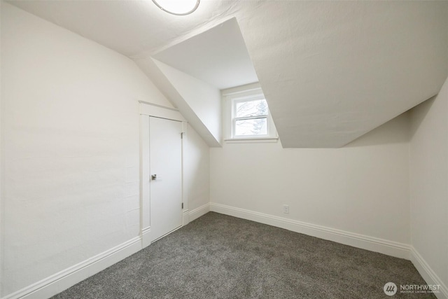 bonus room featuring dark colored carpet, baseboards, and vaulted ceiling