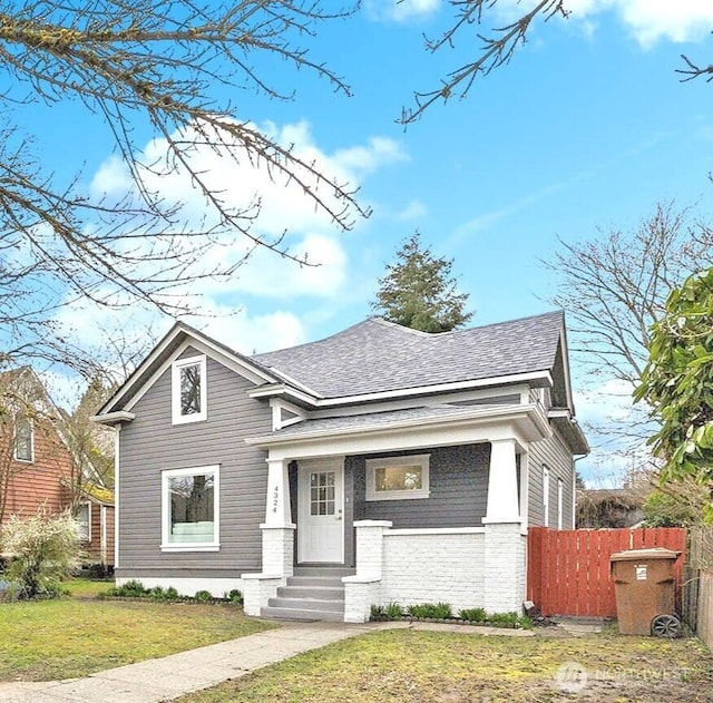 view of front of property featuring a front lawn, fence, and roof with shingles