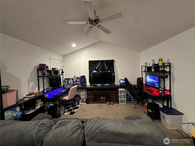 carpeted living room featuring a warm lit fireplace, vaulted ceiling, and ceiling fan