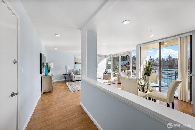 hall featuring recessed lighting, wood finished floors, baseboards, and expansive windows