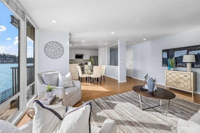 living room with recessed lighting, light wood-style flooring, and baseboards