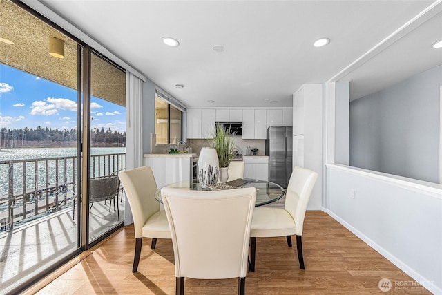 dining area featuring recessed lighting, baseboards, a wall of windows, and light wood-style flooring