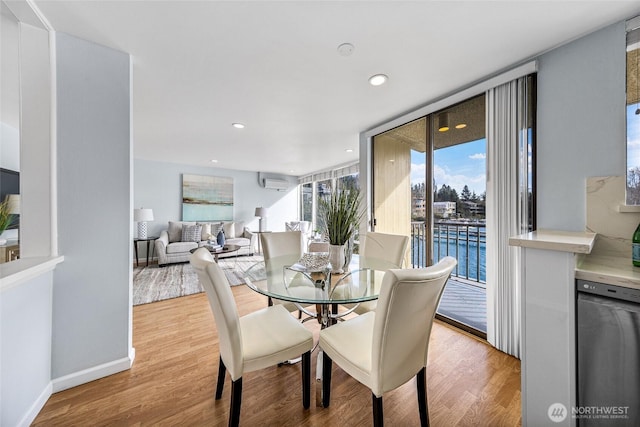 dining room with light wood finished floors, recessed lighting, a wall mounted air conditioner, and baseboards