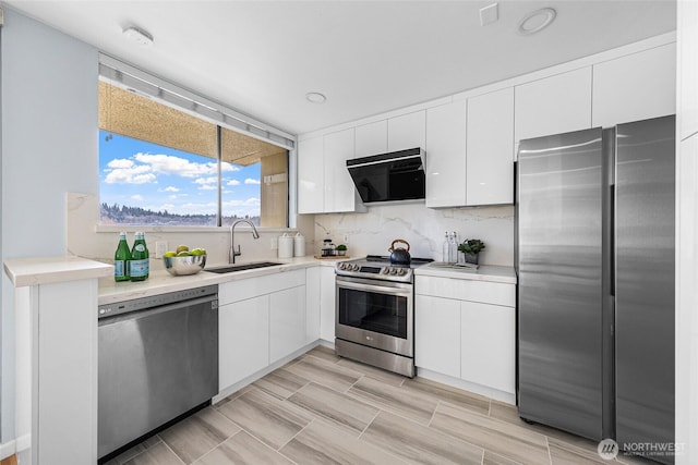 kitchen featuring a sink, decorative backsplash, appliances with stainless steel finishes, and white cabinets