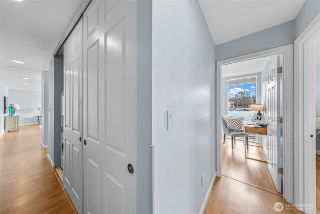 hallway featuring baseboards and light wood finished floors