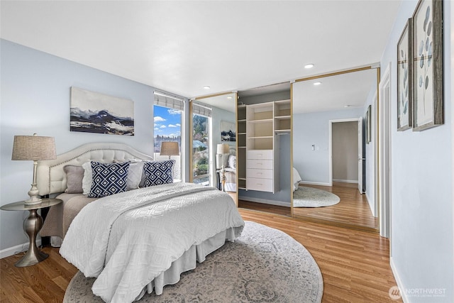 bedroom featuring recessed lighting, expansive windows, baseboards, and wood finished floors