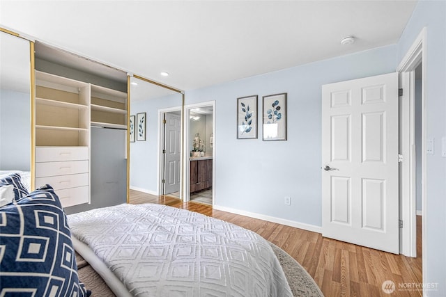 bedroom with ensuite bath, baseboards, and light wood-type flooring