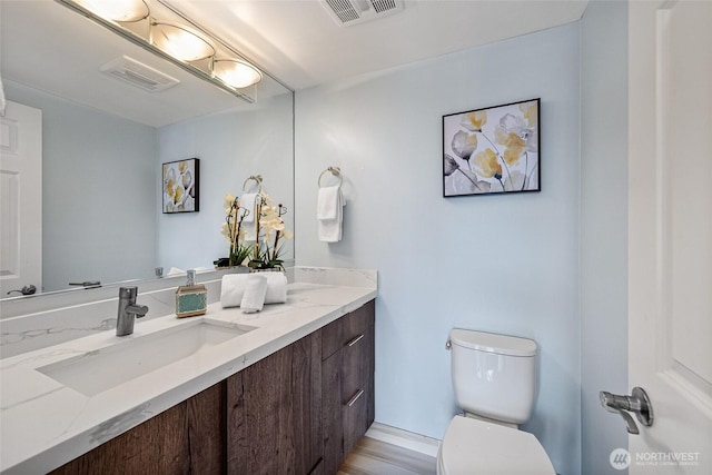 half bathroom with vanity, toilet, and visible vents