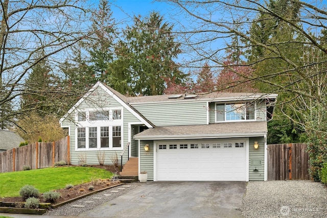 traditional-style home with aphalt driveway, an attached garage, a front yard, and fence