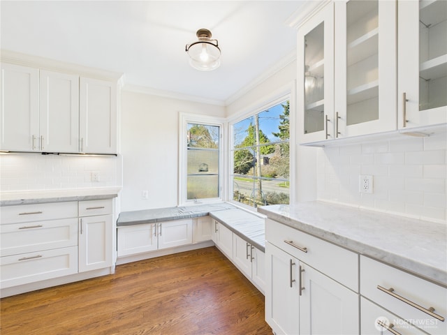 kitchen featuring crown molding, light wood finished floors, glass insert cabinets, white cabinets, and light stone countertops