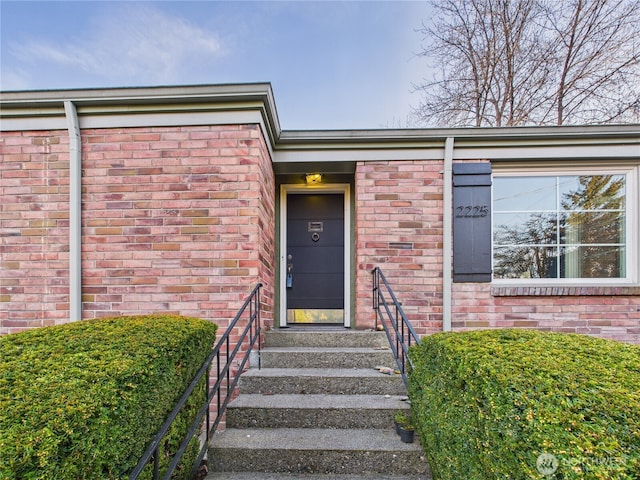 view of exterior entry featuring brick siding