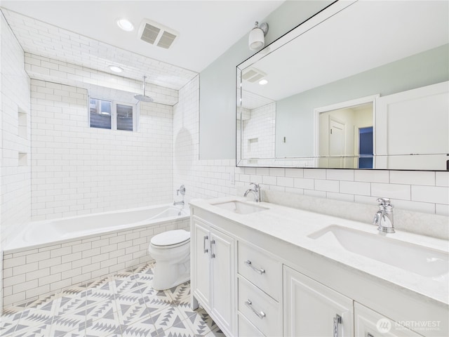 full bath with toilet, tile walls, a sink, and a combined bath / shower with rainfall shower