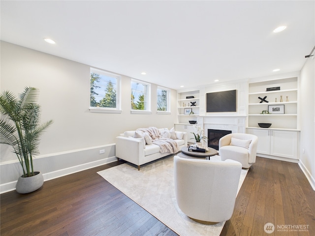 living area featuring recessed lighting, baseboards, dark wood-style flooring, and a glass covered fireplace