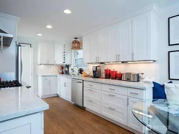 kitchen featuring white cabinets, light countertops, dishwasher, and wood finished floors