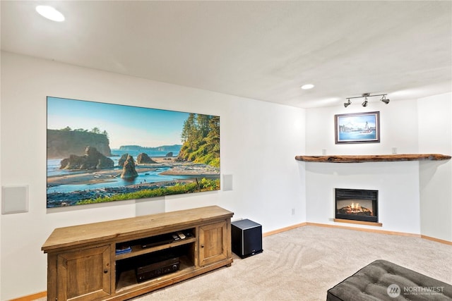 carpeted living area featuring rail lighting, a lit fireplace, baseboards, and recessed lighting