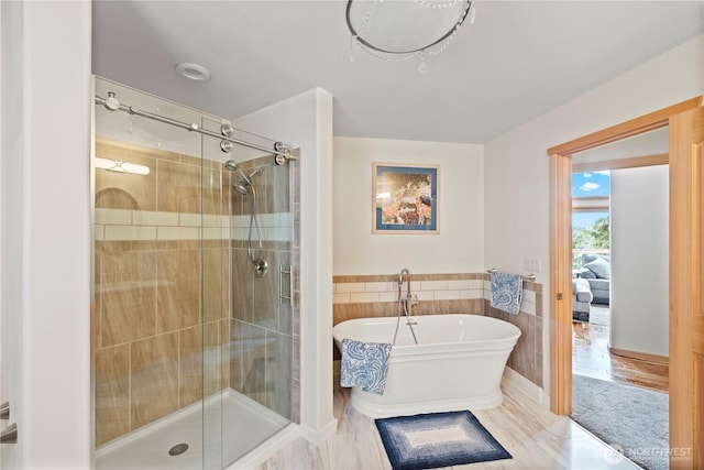 full bath with a stall shower, a freestanding tub, tile walls, and a wainscoted wall