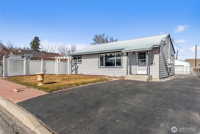 view of front of home featuring metal roof, fence, a front lawn, and a gate