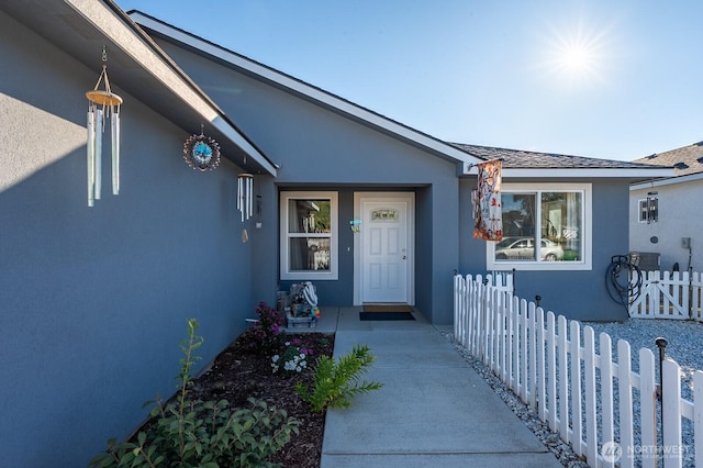 doorway to property with fence and stucco siding