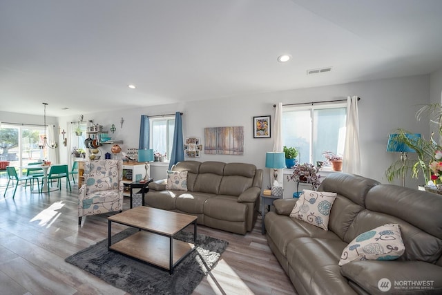 living room with light wood-type flooring, visible vents, and recessed lighting