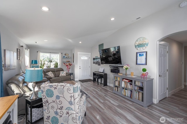 living room featuring arched walkways, recessed lighting, visible vents, wood finished floors, and baseboards