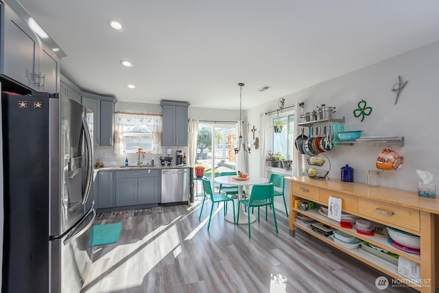 kitchen featuring light wood finished floors, gray cabinets, visible vents, appliances with stainless steel finishes, and a sink