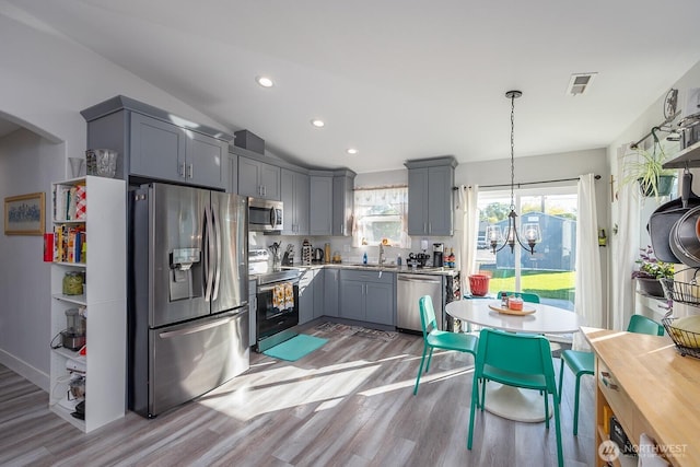 kitchen with light wood-style floors, gray cabinets, stainless steel appliances, and a sink