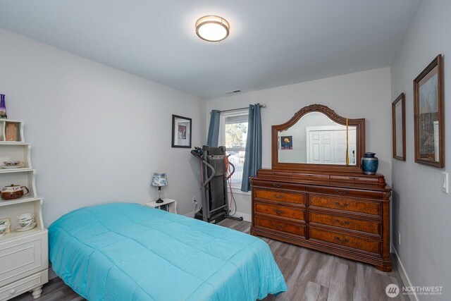 bedroom with visible vents, baseboards, and wood finished floors