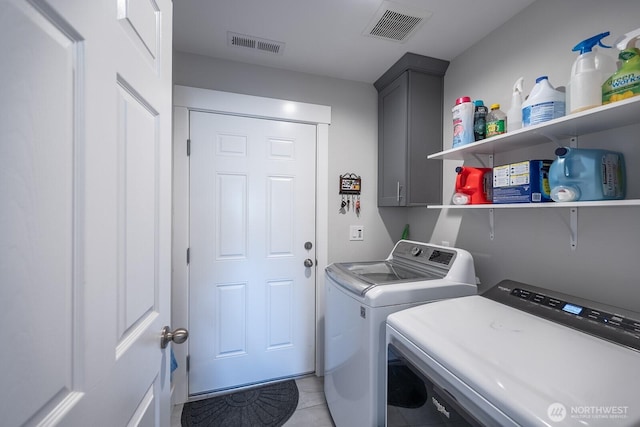 laundry room with washer and clothes dryer, cabinet space, and visible vents