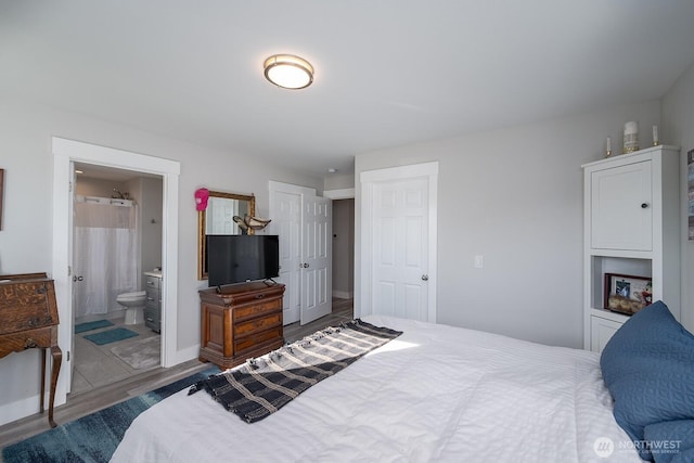 bedroom with wood finished floors, connected bathroom, and baseboards