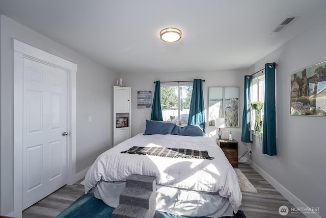 bedroom with visible vents, baseboards, and wood finished floors