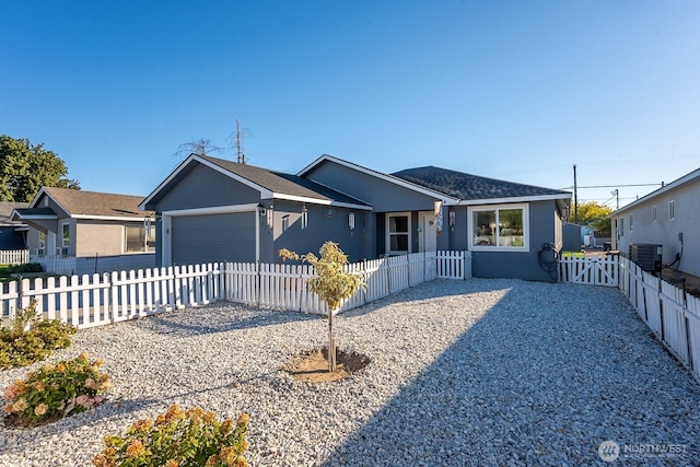 view of front facade with a fenced front yard, stucco siding, an attached garage, and central air condition unit