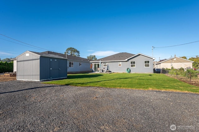 back of house with a yard, an outdoor structure, fence, and a shed