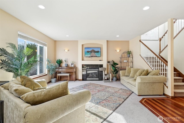 living area with recessed lighting, stairway, light carpet, and a high end fireplace