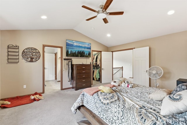 bedroom featuring a walk in closet, vaulted ceiling, light carpet, a closet, and a ceiling fan