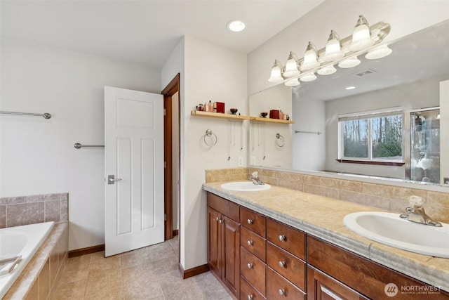 bathroom featuring double vanity, a relaxing tiled tub, visible vents, and a sink