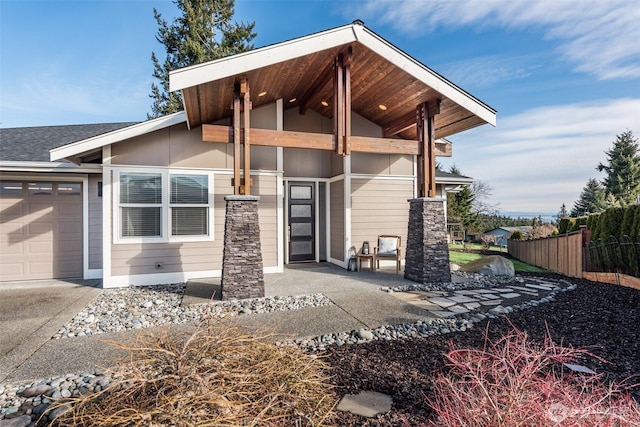 exterior space featuring roof with shingles, an attached garage, and fence