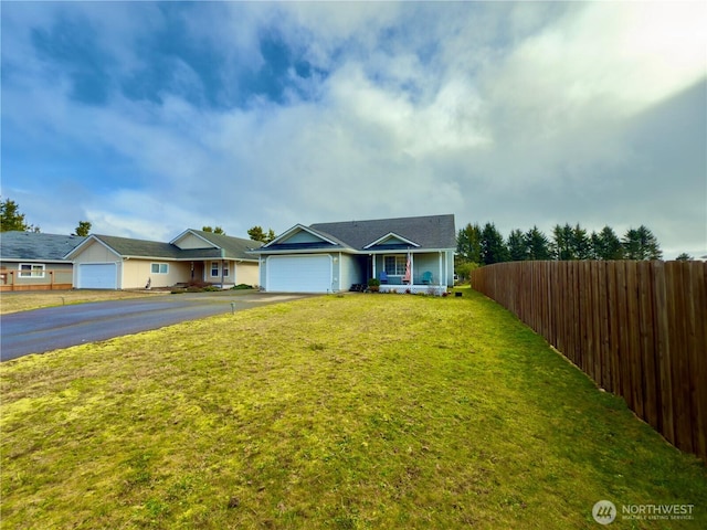 view of front facade featuring a garage, driveway, a front yard, and fence