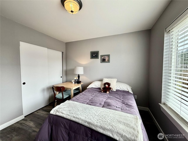 bedroom with dark wood-style floors, a closet, and baseboards