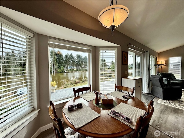 dining area featuring lofted ceiling, baseboards, and wood finished floors