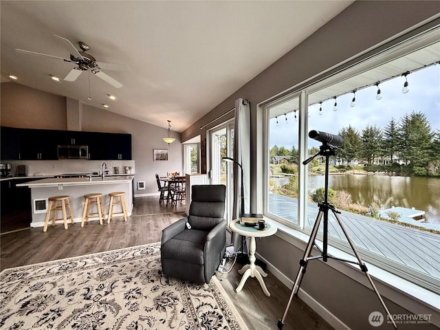 interior space featuring vaulted ceiling, a water view, wood finished floors, and baseboards