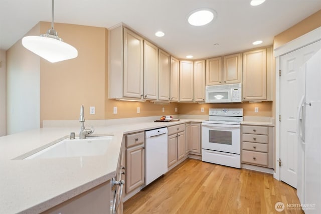 kitchen with white appliances, light wood-style flooring, a sink, and recessed lighting