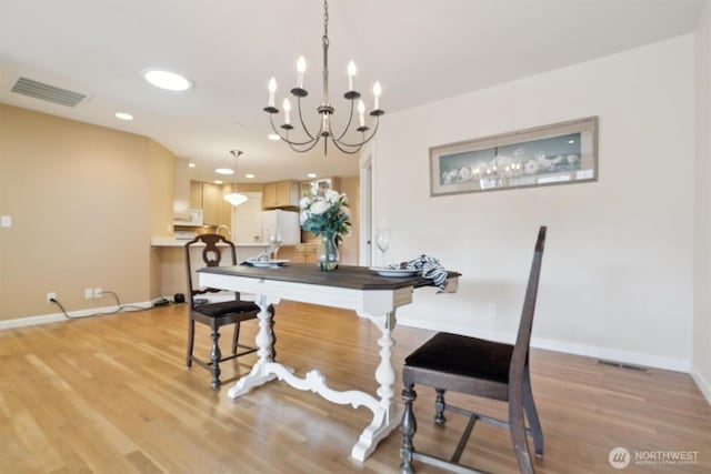 dining space featuring light wood-style floors, baseboards, visible vents, and a notable chandelier