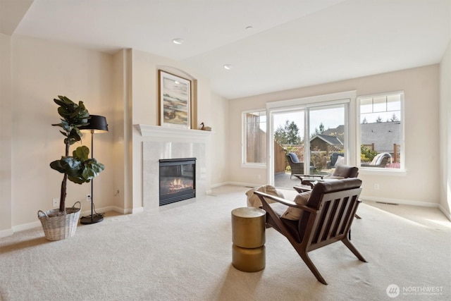 living area featuring a premium fireplace, carpet flooring, and baseboards