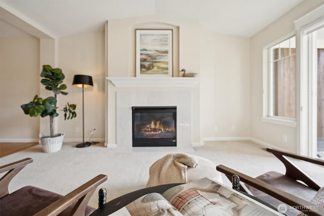 living room featuring baseboards, carpet flooring, and a high end fireplace