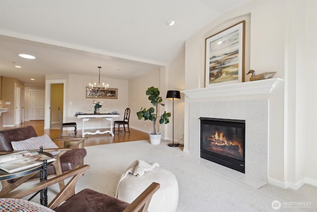 living room featuring a tile fireplace, a notable chandelier, baseboards, and recessed lighting